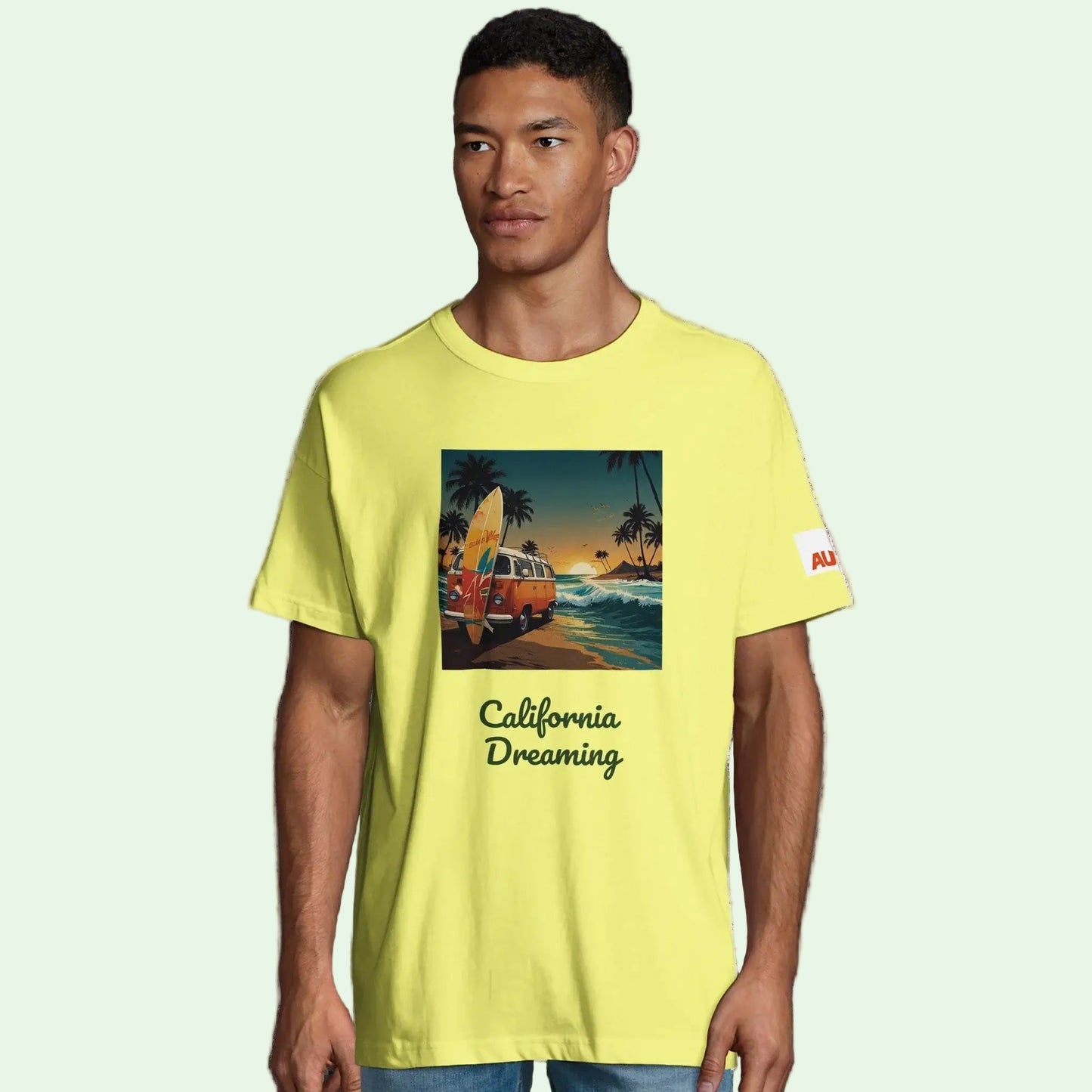 Camiseta Oversize Algodón Orgánico en color amarillo con diseño California Dreaming y surfero en la playa.