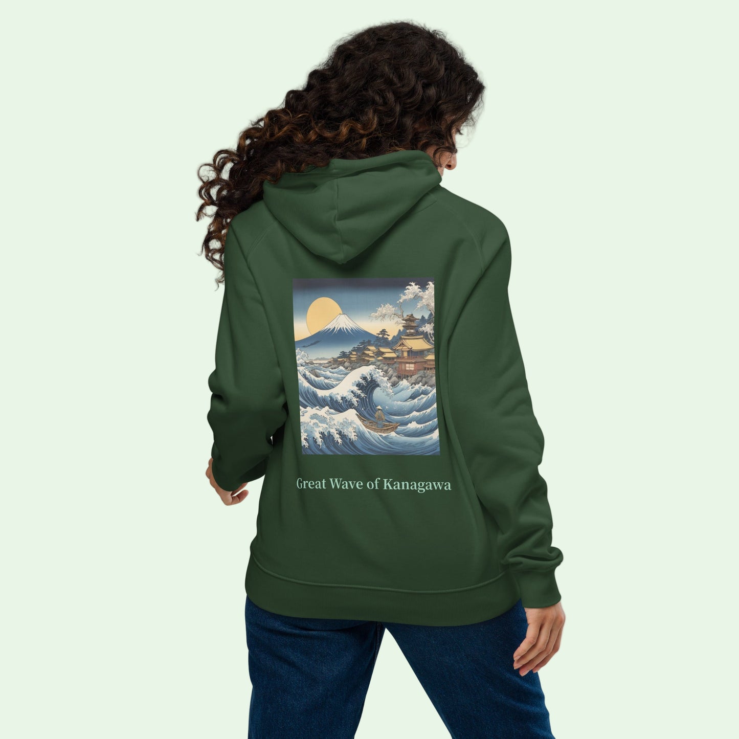woman wearing unisex eco ranglan hoodie in bottle green with great japanese wave back design by Aunti